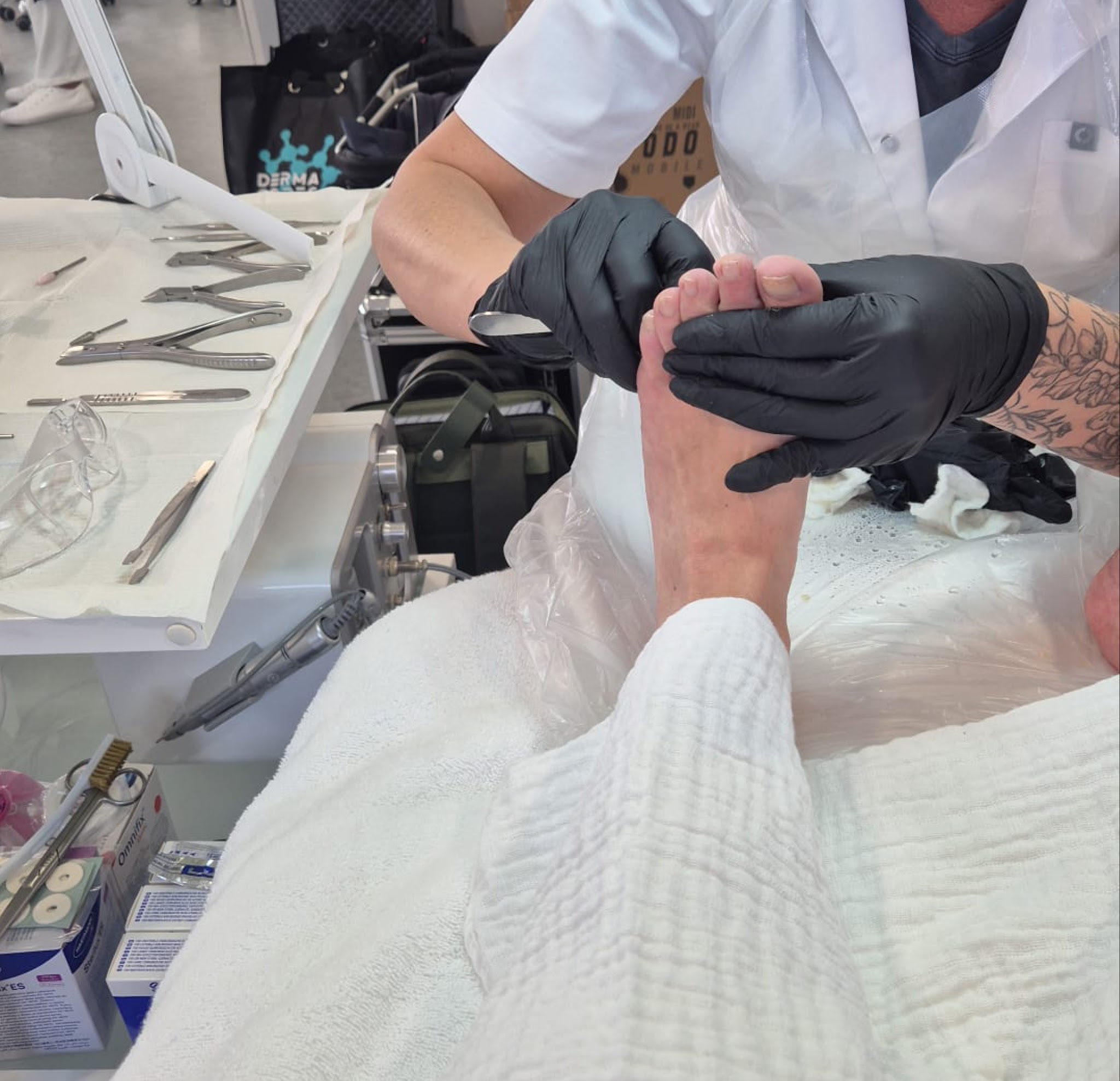 Gehandschoende handen behandelen een voet, met de instrumenten klaar op het blad